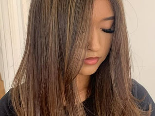 Client with blended brown highlights and long, face-framing layers styled with a smooth, voluminous finish.
