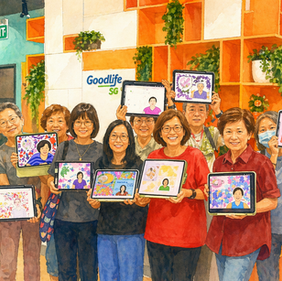 Group of smiling people holding tablets with colorful drawings, standing in a room with orange shelves and plants. "GoodLife SG" sign visible.