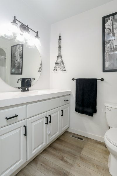 Main-floor bathroom after renovation with new vanity, flooring and lighter paint. Eiffel Tower door on the wall in the white and black bathroom.