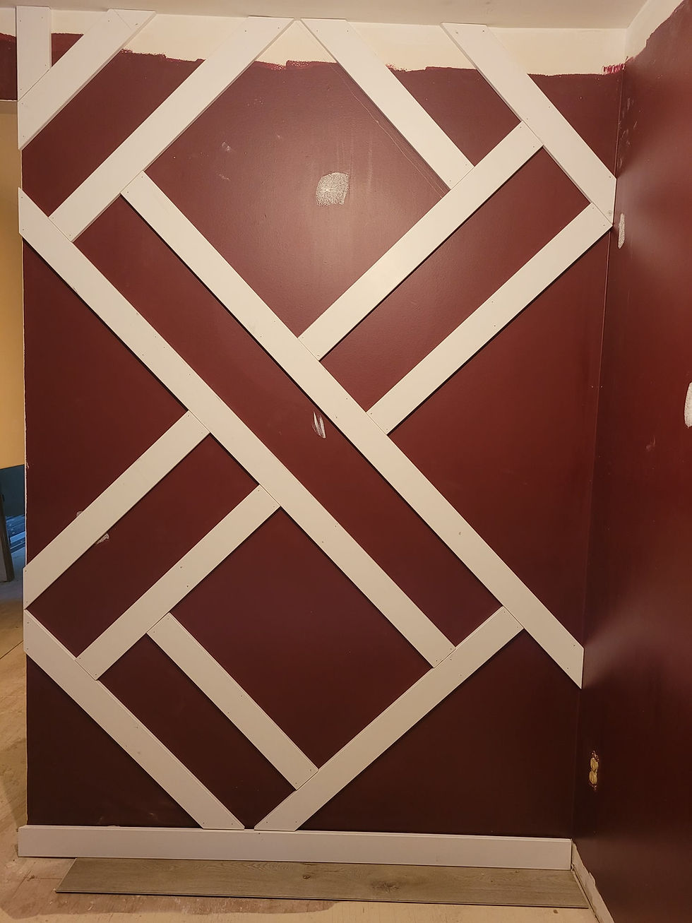 Red wall with white diagonal wooden slats forming a crisscross pattern for a home renovations accent wall to add character to the dining room.