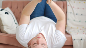 Woman in white shirt uses phone upside down on a pink couch representing Instagram social media engagement tips from Brittany Miller Socials.