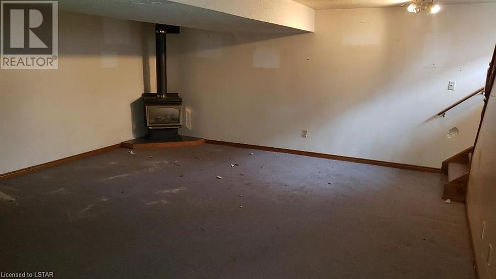 Empty beige basement family room with wood-burning furnace before renovation.