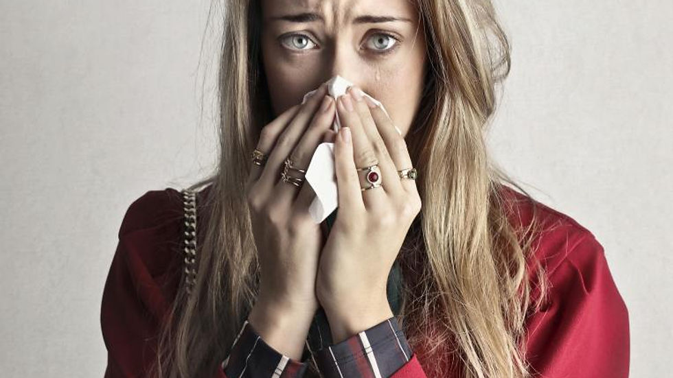 Portrait of a woman sneezing with a tissue, depicting flu symptoms.