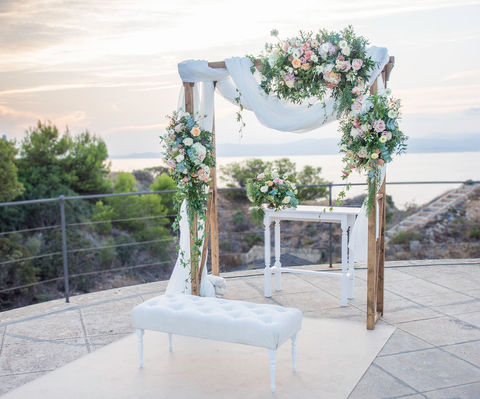 Wedding arch with fabrics and flower decoration with light colors, white and green in front of a spectacular sea view on Majorca.