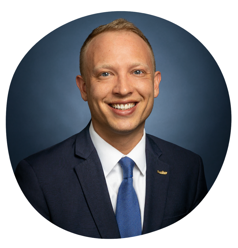 Man smiling and wearing blue suit and blue tie.