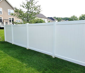 White vinyl privacy fence in a green residential yard.