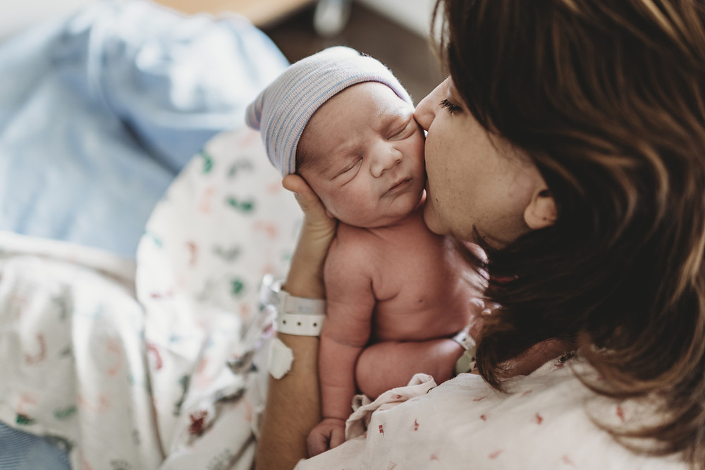 photo of a mother kissing her newborn baby on the cheek
