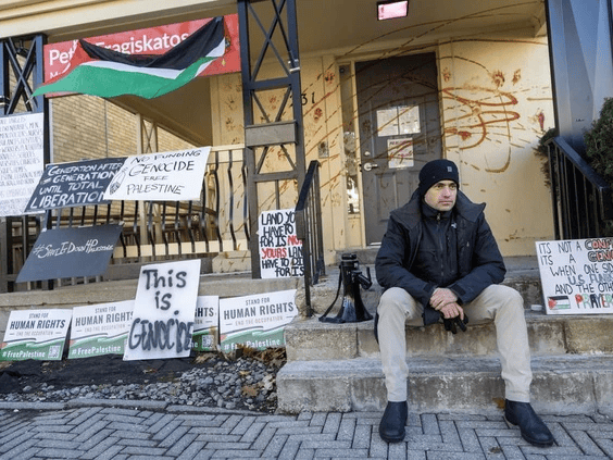 Dr. Tarek Loubani sits outside MP Peter Fragiskatos’s London office after spraying ketchup on the building during a protest