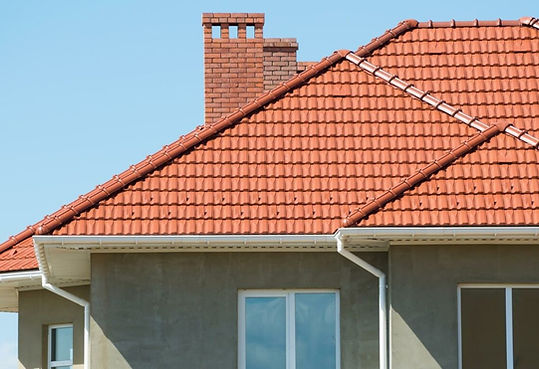 "Completed roof repair with new clay tiles, showcasing a neatly restored rooftop under a clear blue sky."