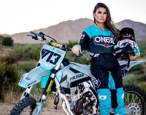 Beautiful woman modeling next to dirt bike motorcycle
