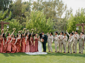 Bridesmaids on the bride’s side and groomsmen on the groom’s side cheering joyfully as the couple shares a kiss
