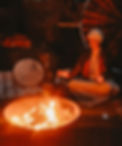 A Picture of MAyu sitting by the Fire, holding a Cacao Ceremony.