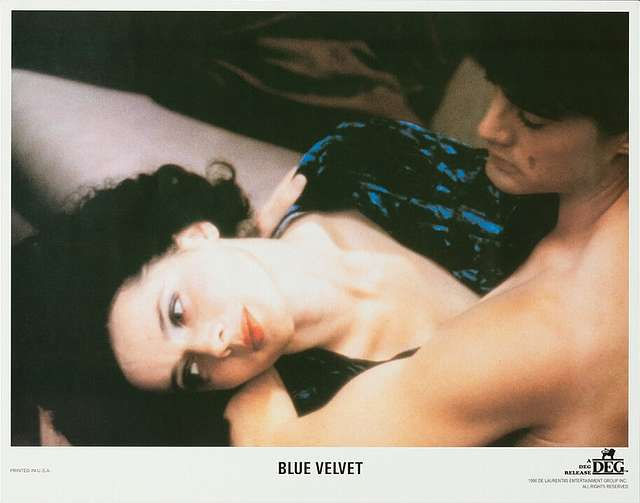 Lobby card from David Lynch’s “Blue Velvet” (1986) featuring Isabella Rossellini lying beside Kyle MacLachlan in an intimate, unsettling scene.