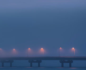 Un ponte nella nebbia appena rischiarato dalla luce soffusa dei lampioni, sul far della sera. Richiama sentimenti di dubbio ed incertezza