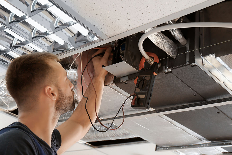 Technician installing HVAC and electrical services above a suspended ceiling grid in a commercial building in Ireland