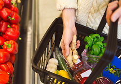 person putting food into a shopping basket