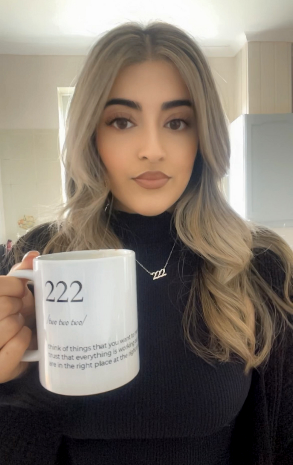 Face behind the brand, showcasing Angel Number mug in 222, and wearing Angel Number necklace 222