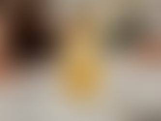 A cocktail with ice, lemon, citrus slice, and thyme on a marble bar counter. Copper bar tools and glassware in the blurred background.