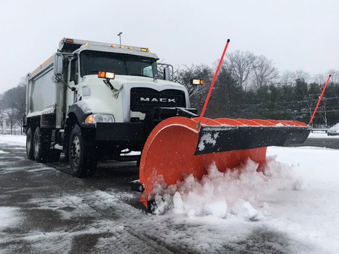 Large snow plow attached to Mack truck clearing snow from road