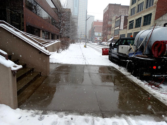 Section of snow covered sidewalk completely cleared after using liquid deicer