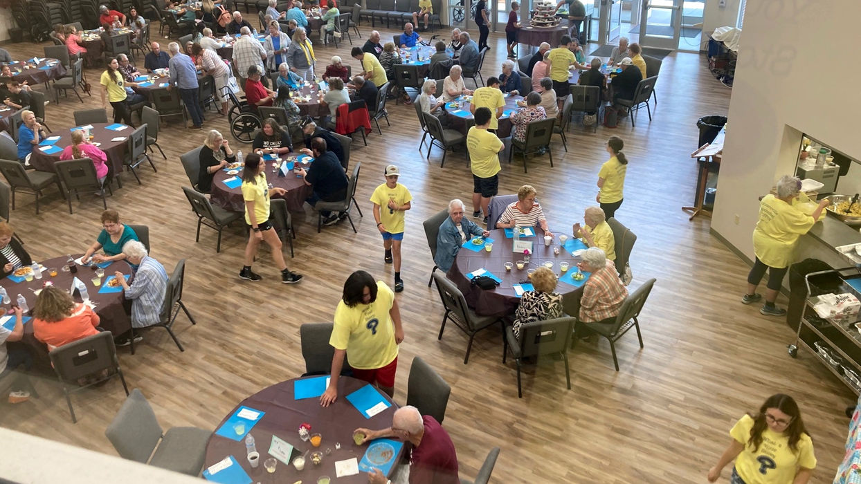 Several round tables filled with people in large church event venue during event