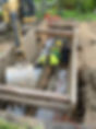 Sewer line being installed by laborers with excavation equipment nearby