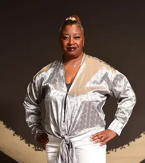 Woman in a silver blouse posing before a circular backdrop
