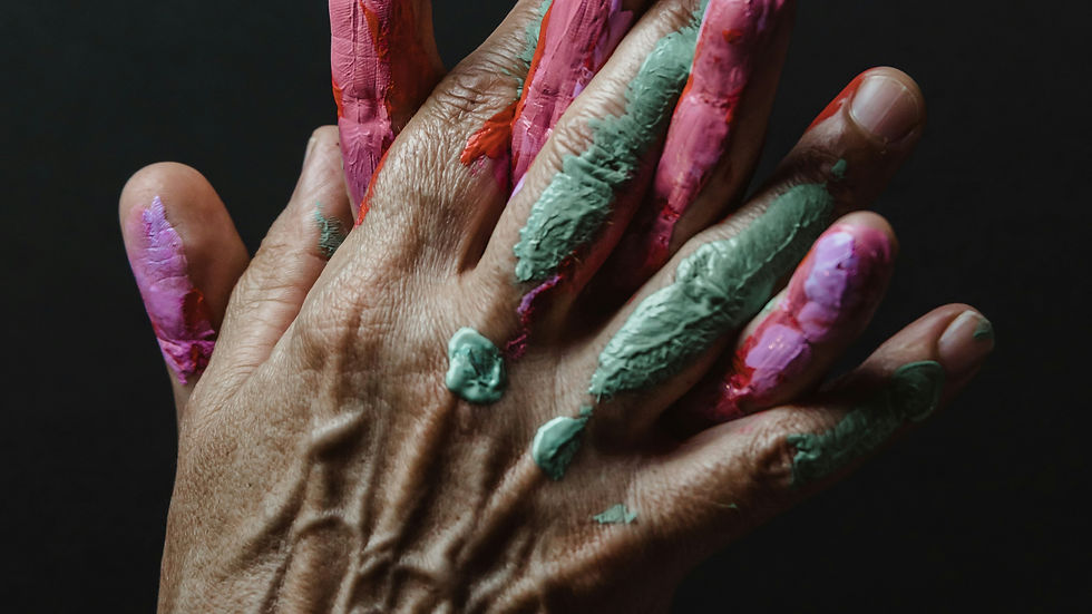 Hands covered in pink and green paint against a dark background, symbolizing the connection between art and mental health, creativity, and self-expression.
