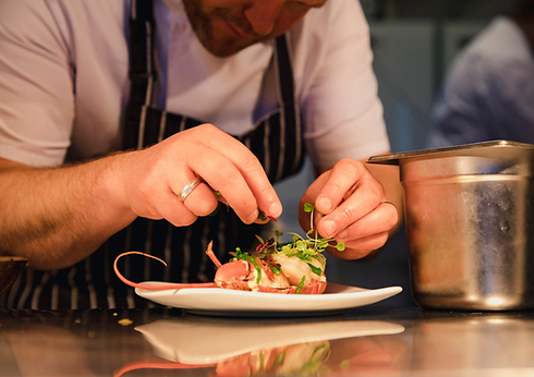 Chef carefully garnishing a dish with fresh sprouts