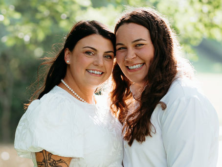 Two brides embrace during their portrait session at the park