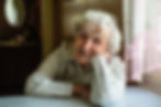 What's too old? Elder woman smiling at the camera while sitting next to a window.