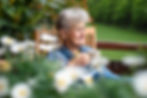 Elder woman relaxing on her balcony surrounded by summer flowers.