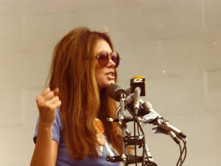 Gloria Steinem speaking at a podium, circa 1970s. Image by Nancy Gee.