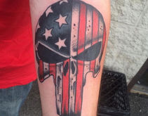 A colored forearm tattoo of Marvel's Punisher skull icon filled in with the American Flag.