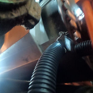 Mangueira preta curvada instalada em superfície laranja, com Montagem de calhas e utensílios de Inox.