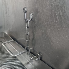 Mecanismo de corrente e gancho de aço inoxidável em equipamento industrial.