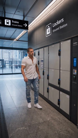 Episode 011: Delvin stands near a row of station storage lockers beneath overhead signs.