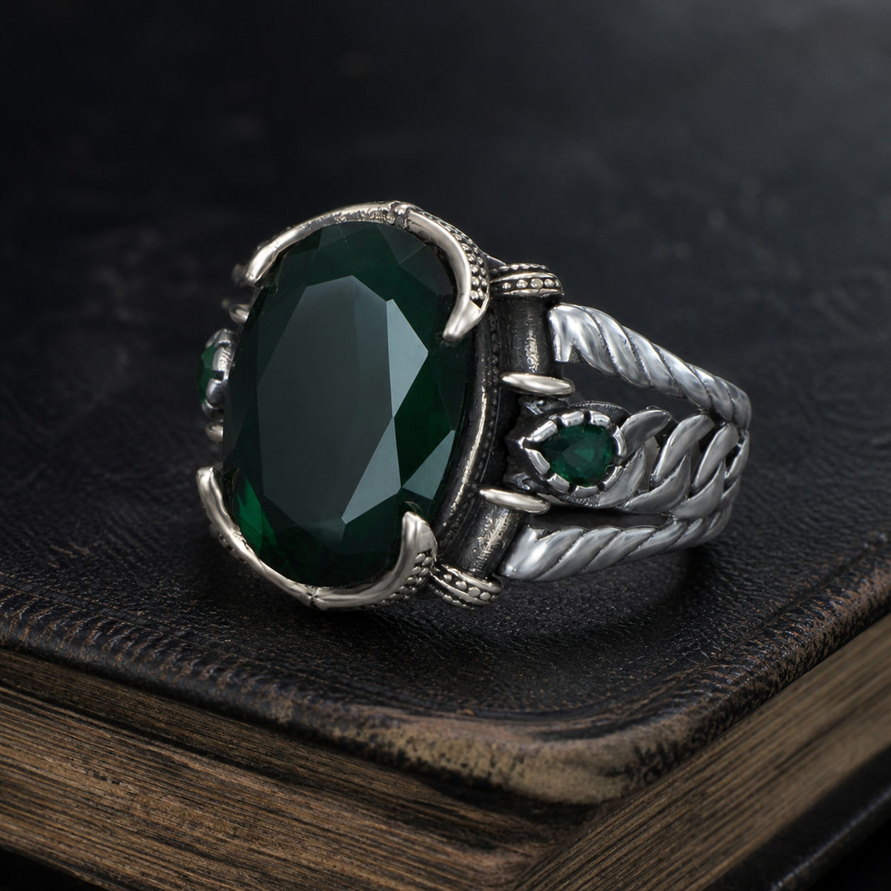 Emerald Green Zircon Leaf Motif Sterling Silver Men's Ring displayed on a black leather antique book