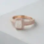 Packshot photography of a rose gold engagement ring with a radiant-cut center diamond. A halo and pave band encircle the stone.