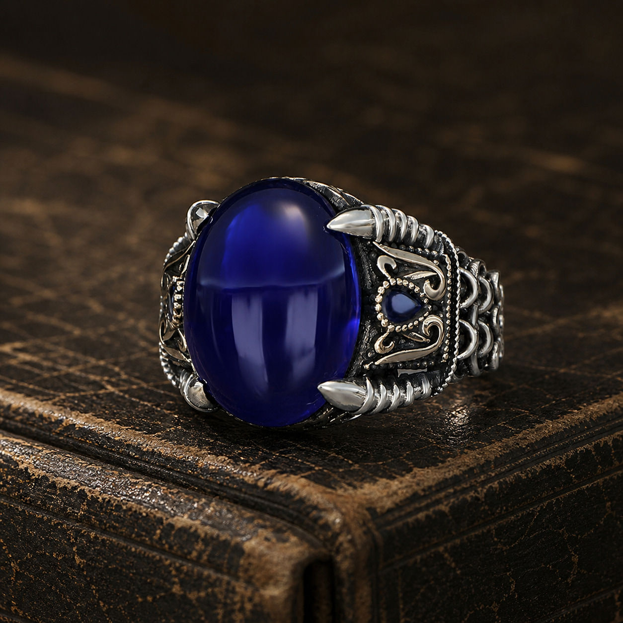 Royal Blue Cabochon Scroll Sterling Silver Men's Ring displayed on a black leather antique book