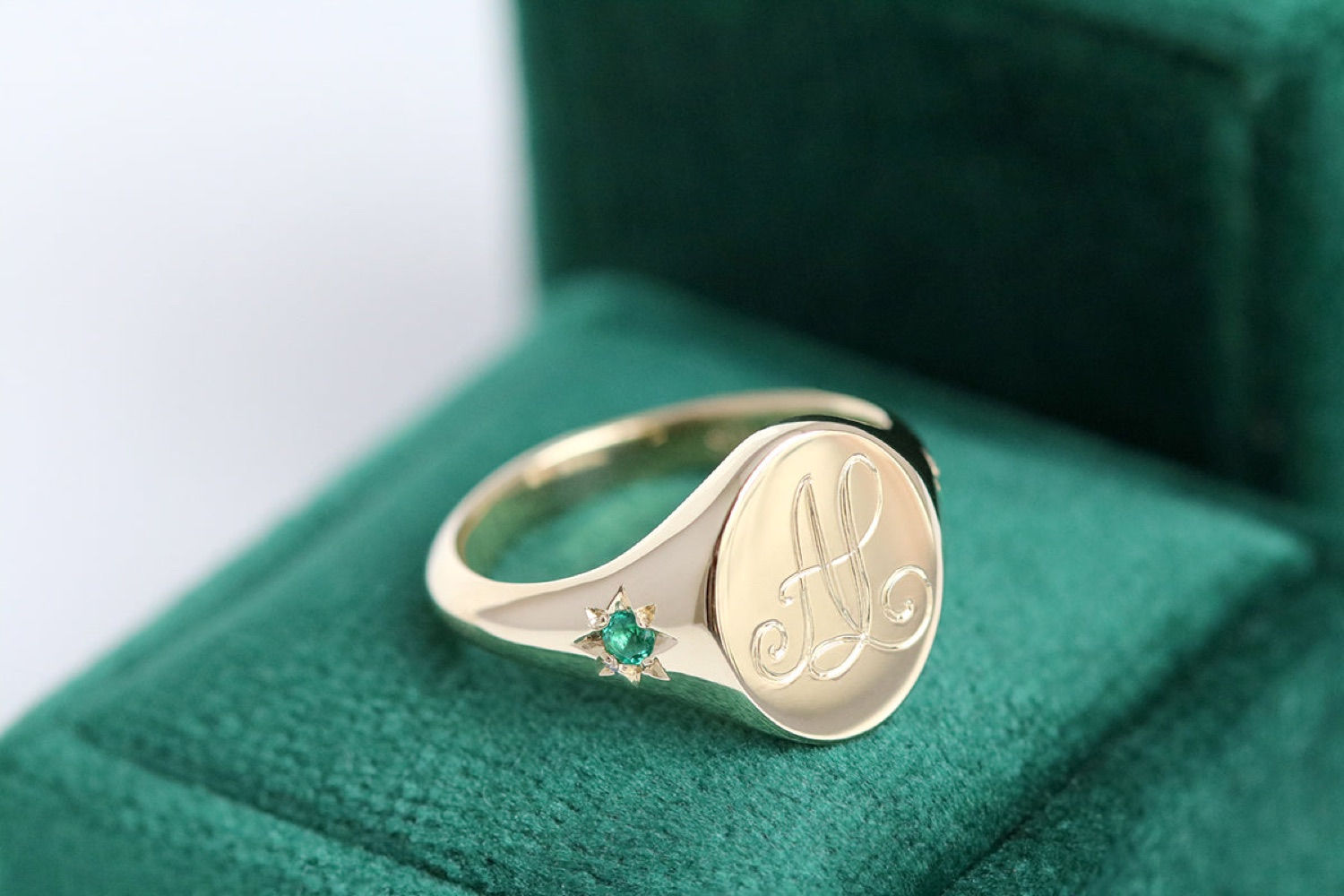Gold emerald monogram oval signet ring with star setting.