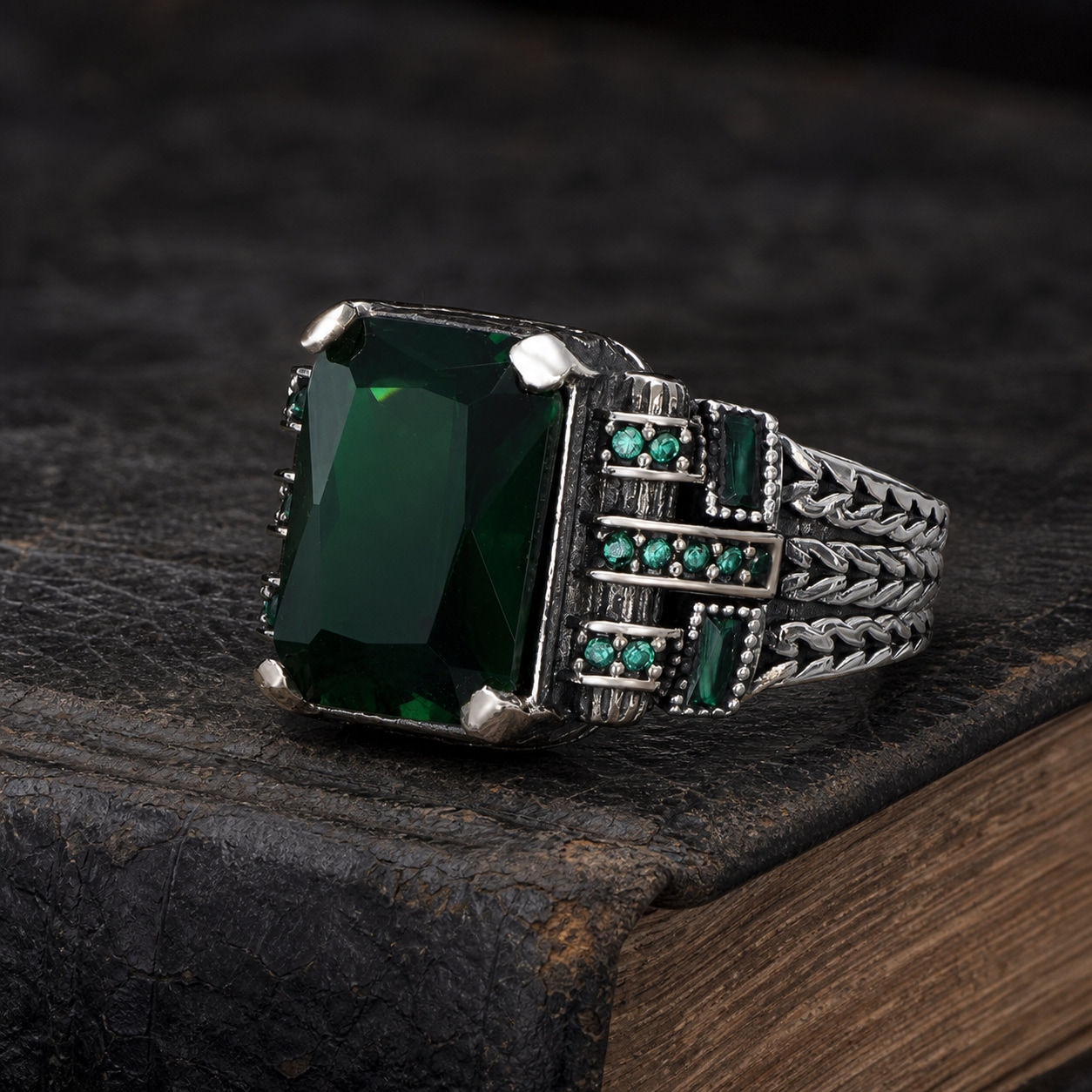 Emerald Zircon Geometric Panel Sterling Silver Men's Ring displayed on a black leather antique book