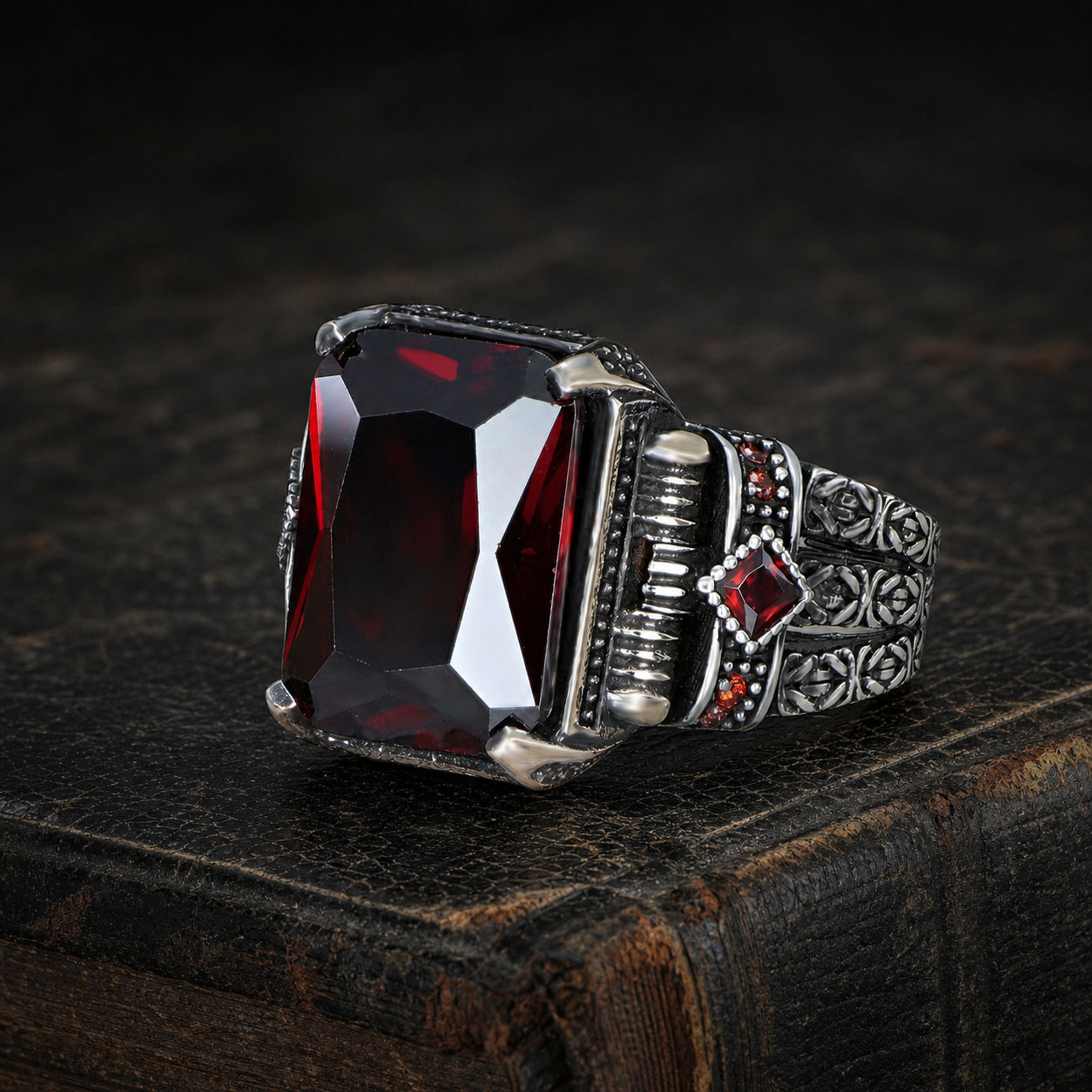 Rectangular Red Zircon Ornate Sterling Silver Men's Ring displayed on an aged black leather antique book