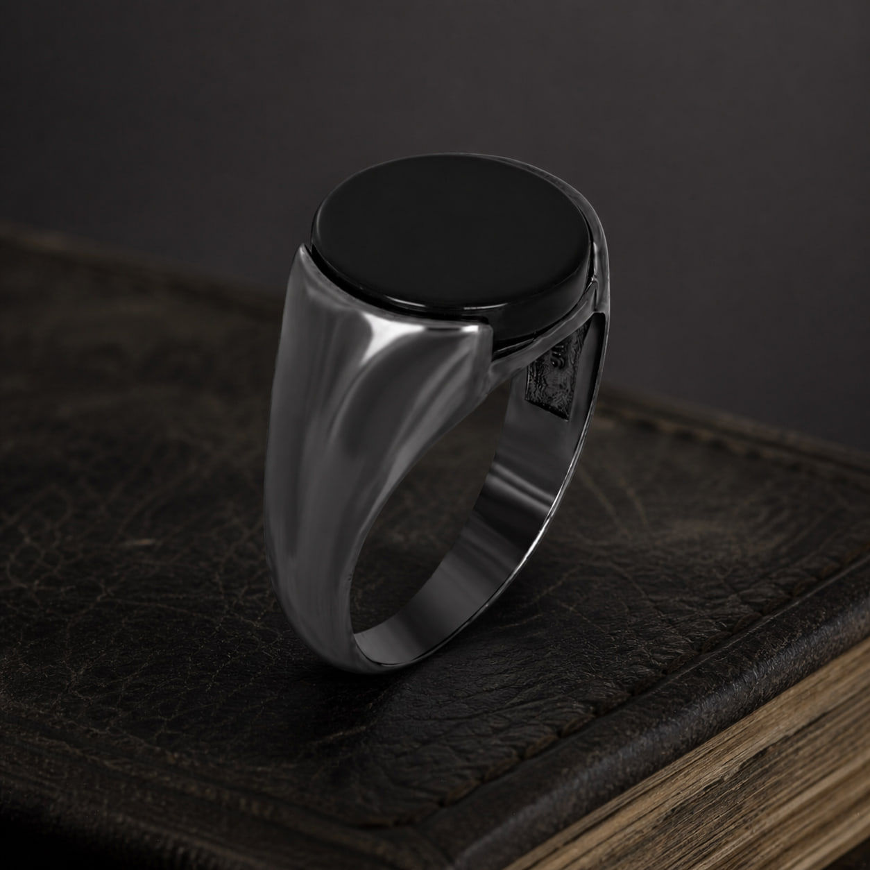 Round Black Onyx Men's Sterling Silver Signet Ring on a black leather book