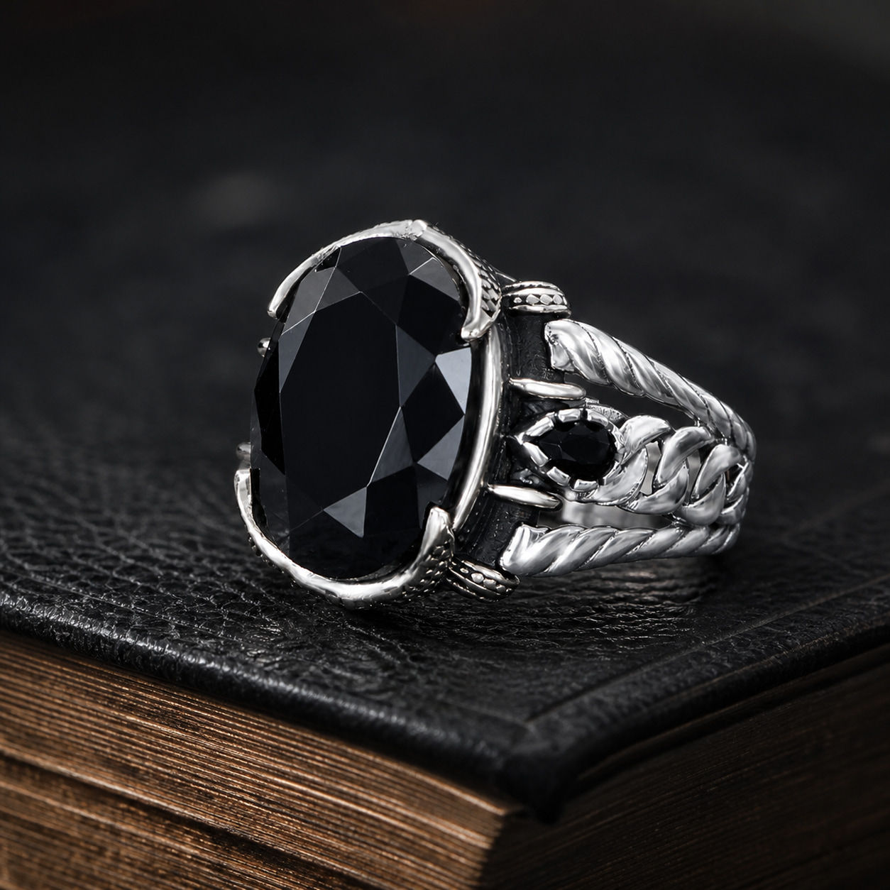 Black Zircon Leaf Motif Sterling Silver Men's Ring displayed on a black leather antique book