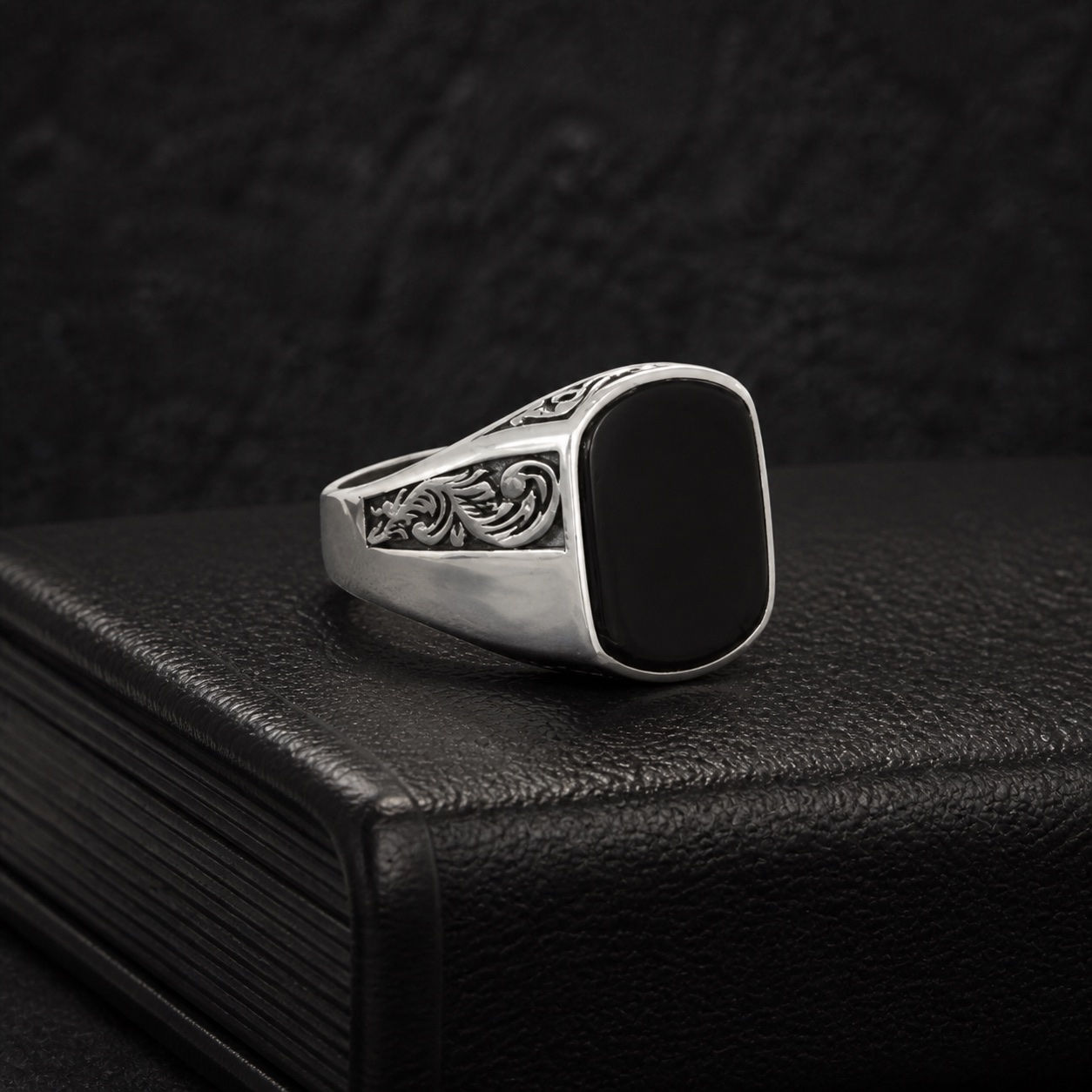 Black onyx silver men's ring with acanthus engraving on black leather book