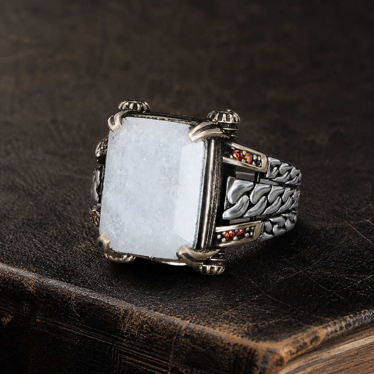 White Paraiba Braided Chain Sterling Silver Men's Ring displayed on a black leather antique book