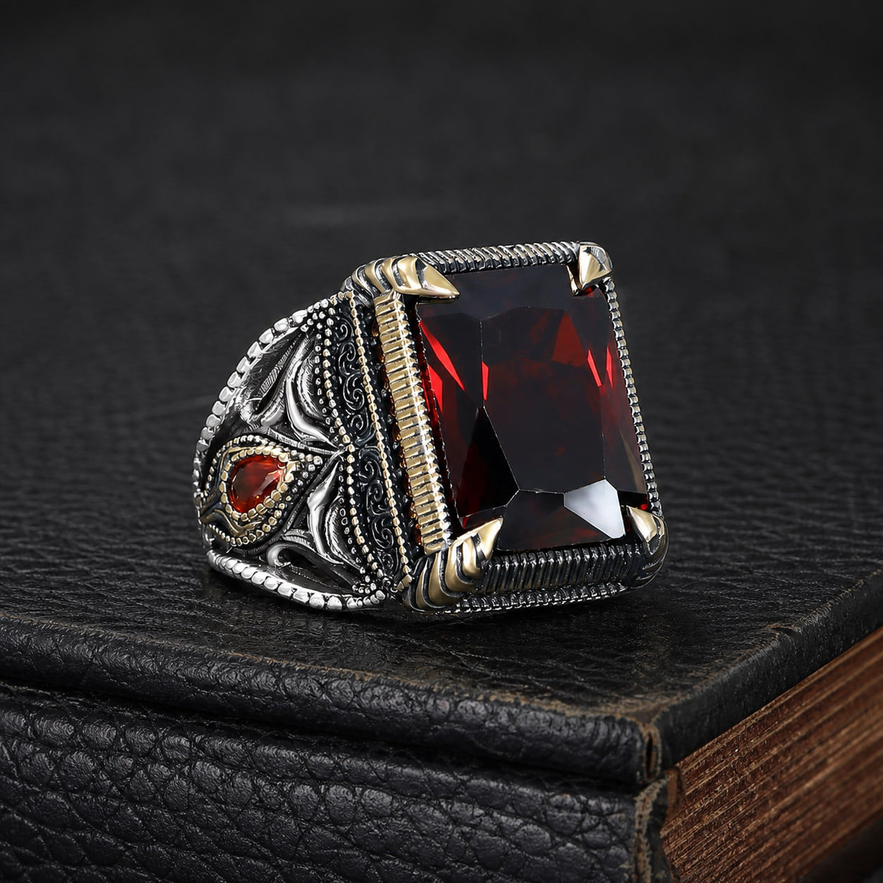 Hand Engraved Red Zircon Men's Sterling Silver Ring on a black leather book