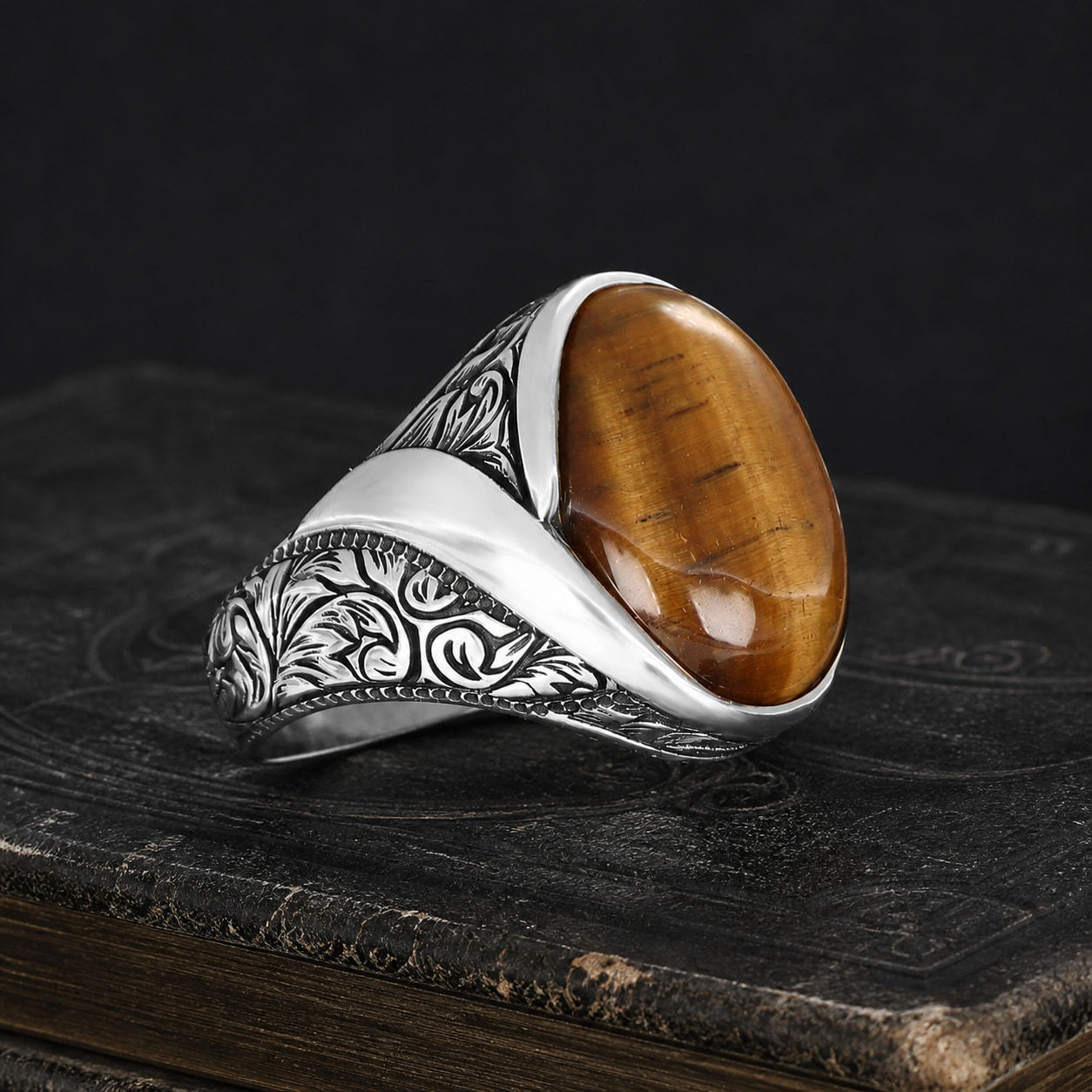 Tiger Eye Engraved Sterling Silver Men's Ring on a black leather book