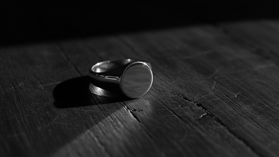 Close-up view of a polished silver ring on a dark wooden surface
